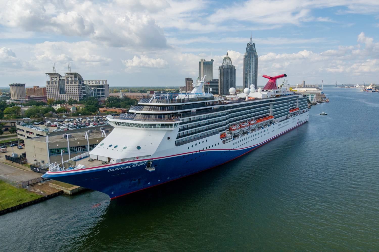 Cruise ship docked along Mobile’s waterfront with the downtown skyline and convention center visible in the background