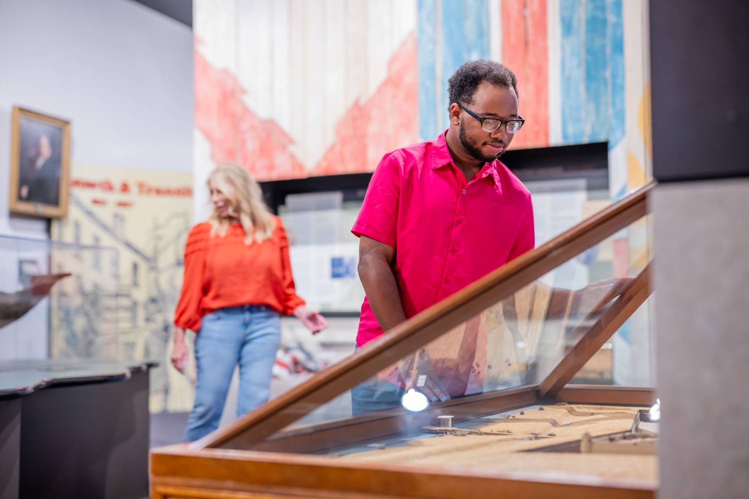 Visitors exploring historical exhibits and display cases inside a museum gallery.