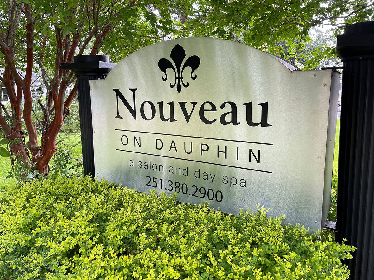 Sign for Nouveau on Dauphin salon and day spa surrounded by landscaped greenery and trees.